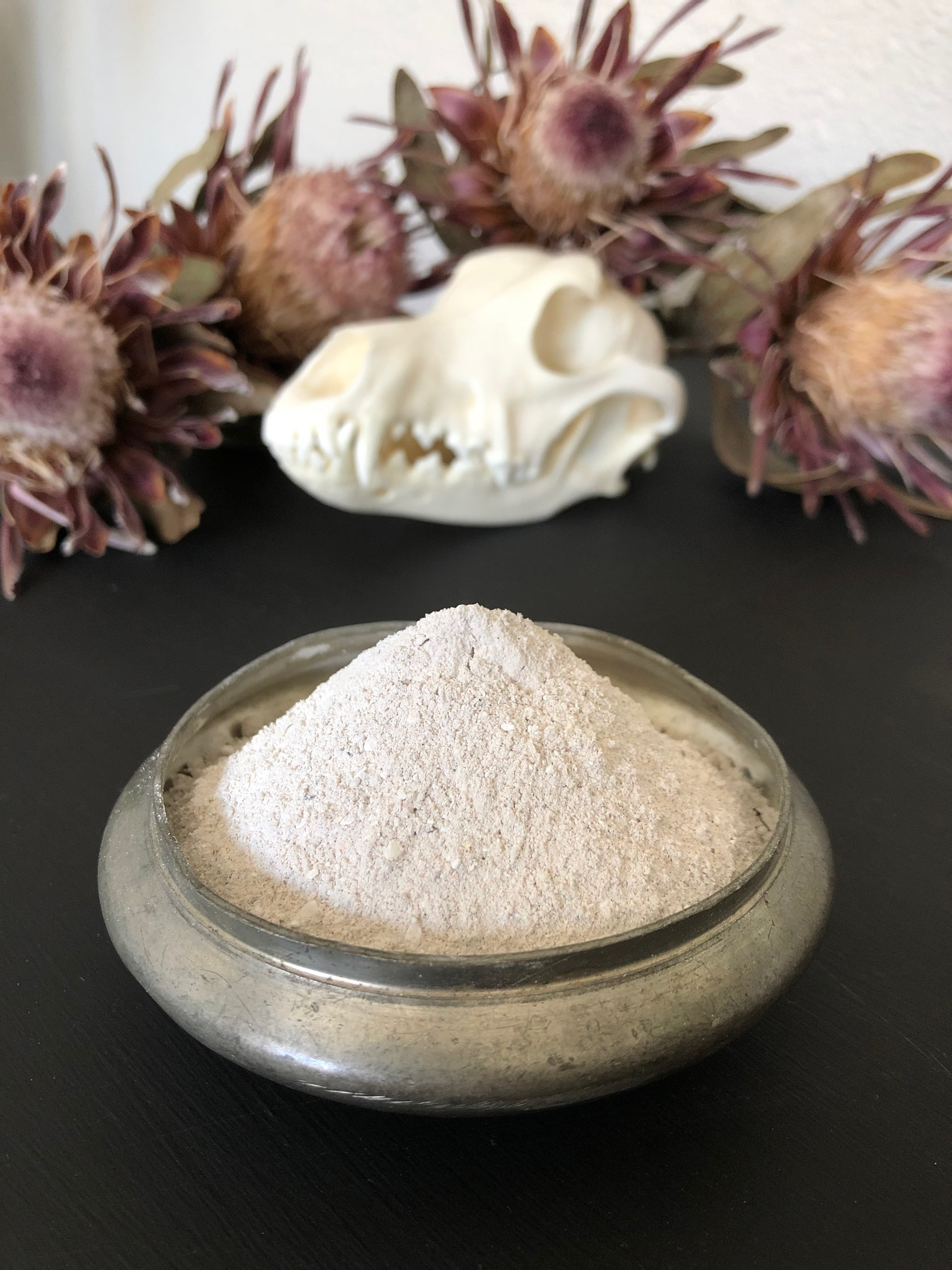 Ashes in a saucer with a skull and flowers in the background