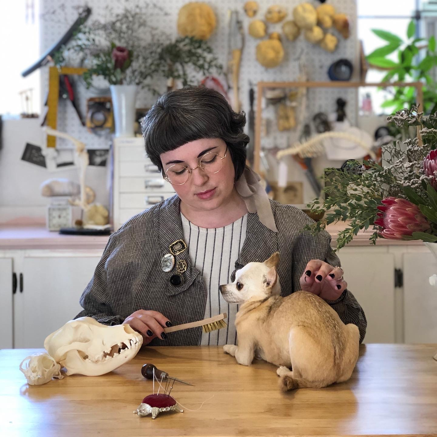 Lauren in her workshop next to a skull and a taxidermied dog